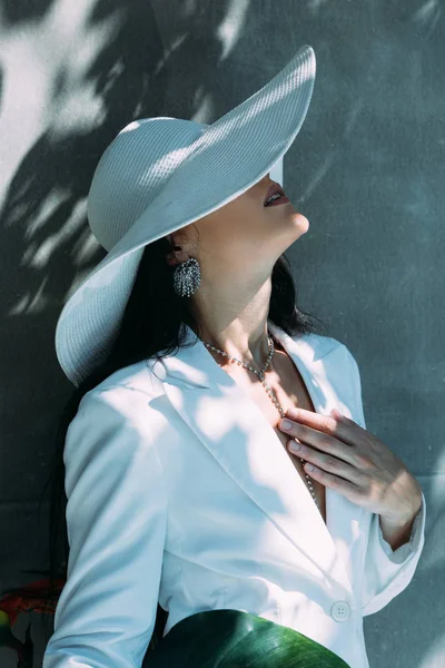 Femme adulte en costume blanc et chapeau posant à l'extérieur — Photo de stock