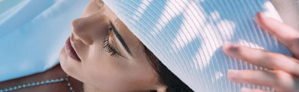 Plano panorámico de mujer atractiva en sombrero blanco posando con los ojos cerrados afuera - foto de stock