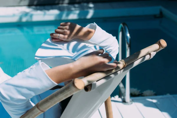 Vista trasera de la mujer en el sombrero blanco sentado om silla de cubierta exterior - foto de stock