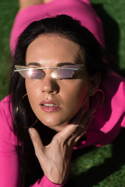 Attrayant femme en robe et lunettes de soleil posant et regardant la caméra à l'extérieur — Photo de stock
