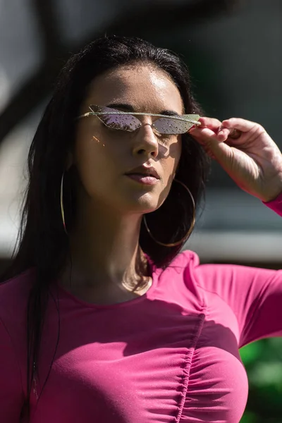 Mulher atraente em vestido e óculos de sol posando e olhando para a câmera fora — Fotografia de Stock