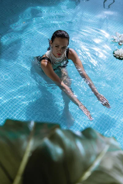 Messa a fuoco selettiva di donna attraente in collana di perle nuoto in piscina — Foto stock