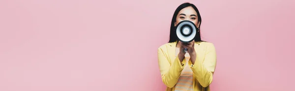 Asiatin im gelben Outfit hält Megafon isoliert auf rosa, Panoramaaufnahme — Stockfoto