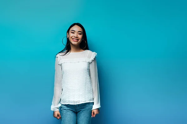 Feliz morena asiática mujer en azul fondo - foto de stock