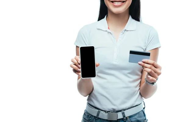 Vista ritagliata di sorridente bruna ragazza asiatica in possesso di carta di credito e smartphone con schermo bianco isolato su bianco — Foto stock