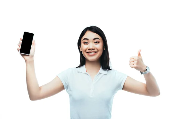 Feliz morena asiática mujer sosteniendo smartphone con pantalla en blanco y mostrando el pulgar hacia arriba signo aislado en blanco - foto de stock