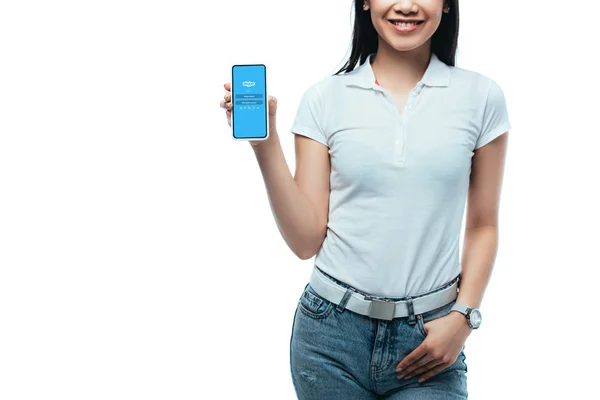 Київ, Україна - 15 липня 2019: Переглянутий погляд на усміхнену брюнетку Азіатську жінку, що тримає смартфон з додатком для скайпу ізольованим на білому — стокове фото