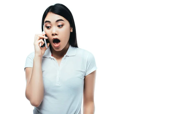 Sorprendido atractivo asiático chica con abierto boca hablando en smartphone aislado en blanco - foto de stock