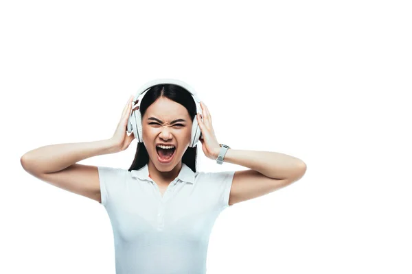 Angry attractive asian girl screaming in headphones isolated on white — Stock Photo