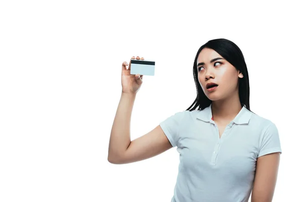 Conmocionado chica asiática mirando tarjeta de crédito aislado en blanco - foto de stock