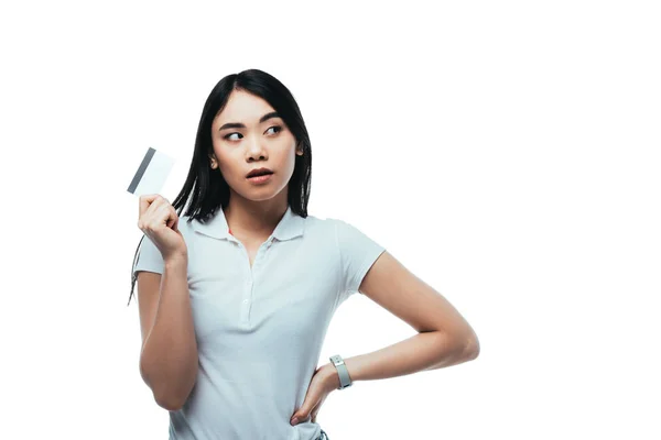 Rêveuse asiatique fille tenant carte de crédit et regardant loin isolé sur blanc — Photo de stock