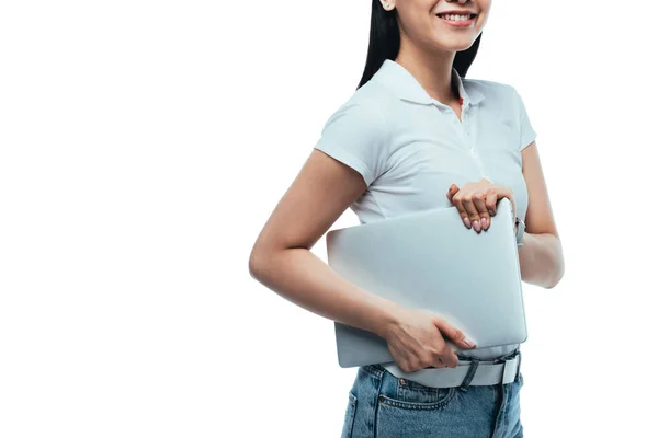 Обрезанный вид улыбающаяся азиатская девушка держит ноутбук изолирован на белом — стоковое фото