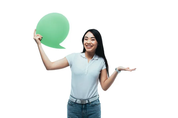 Happy attractive asian girl holding green blank speech bubble isolated on white — Stock Photo