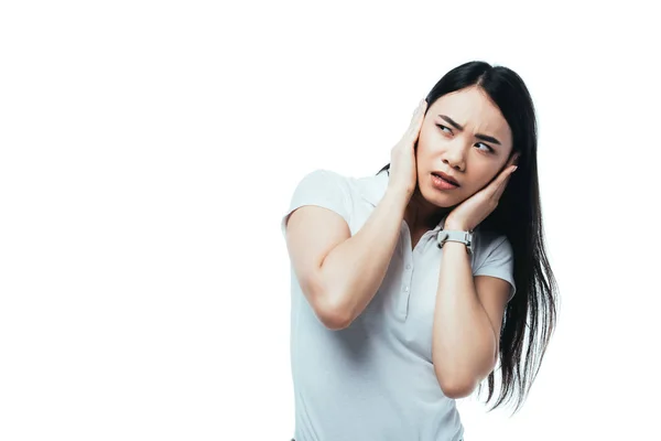 Confundido atractivo asiático chica cubriendo orejas con manos aisladas en blanco - foto de stock