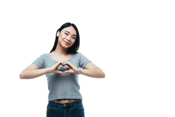 Усміхнена приваблива азіатська дівчина показує жест серця ізольовано на білому — стокове фото