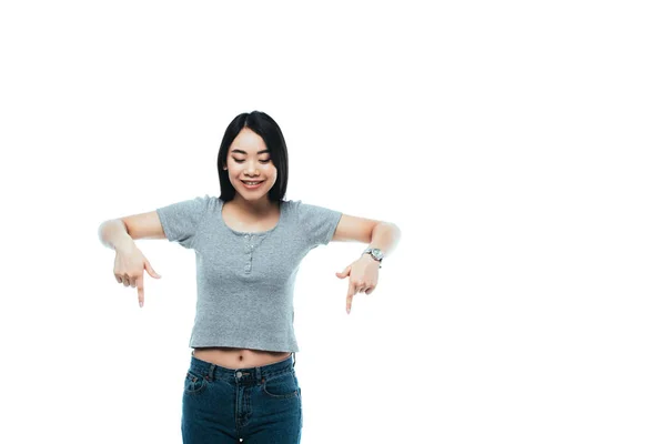 Felice ragazza asiatica che punta con le dita verso il basso isolato su bianco — Foto stock