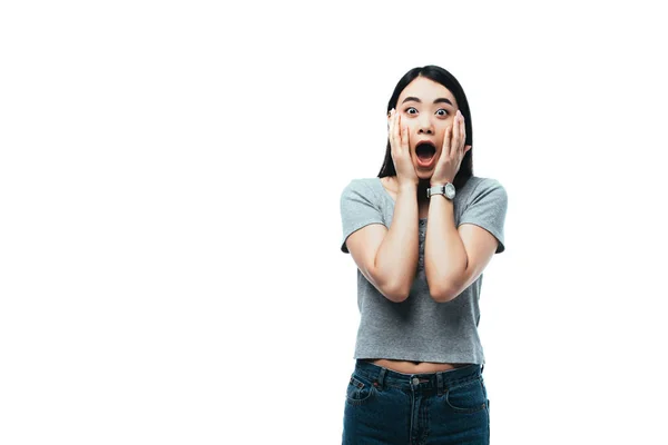 Шокована азіатська дівчина з відкритим ротом торкається обличчя ізольовано на білому — стокове фото