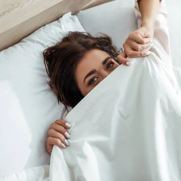 Attraktive Frau, die morgens ihr Gesicht mit einer Decke verdeckt — Stockfoto