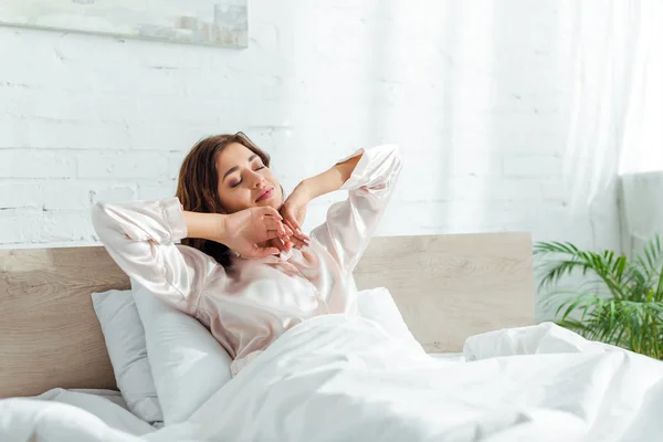 Attractive woman with closed eyes stretching herself at morning — Stock Photo