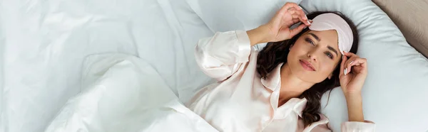 Panoramic shot of attractive woman with sleeping mask looking at camera at morning — Stock Photo