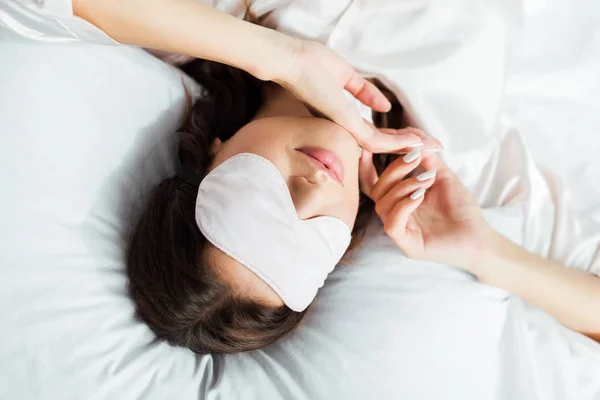 Visão de alto ângulo da mulher em máscara de dormir deitada na cama pela manhã — Fotografia de Stock