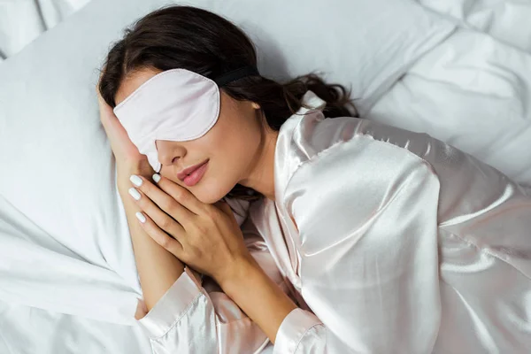 Vista dall'alto della donna in maschera addormentata sdraiata a letto al mattino — Foto stock