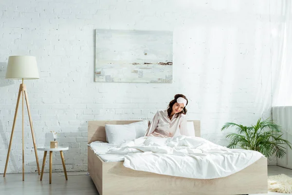 Atractiva mujer en la máscara de dormir mirando a la cámara por la mañana - foto de stock