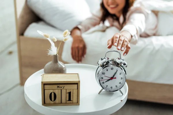 Selective focus of smiling woman taking alarm clock at morning — Stock Photo