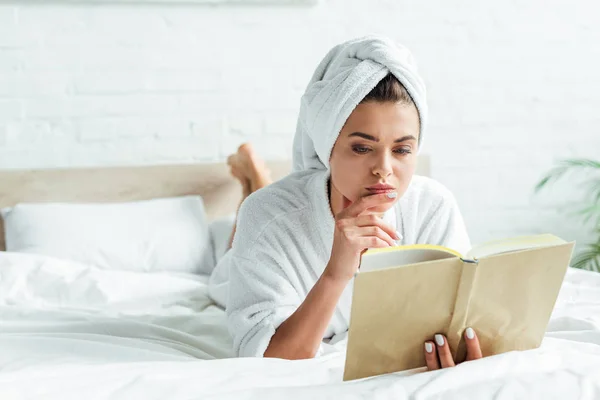 Mulher atraente em toalha e livro de leitura de roupão de banho de manhã — Fotografia de Stock