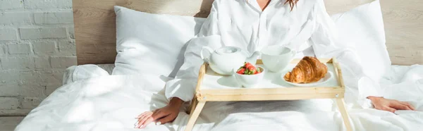 Colpo panoramico di donna in camicia bianca che fa colazione a letto al mattino — Foto stock