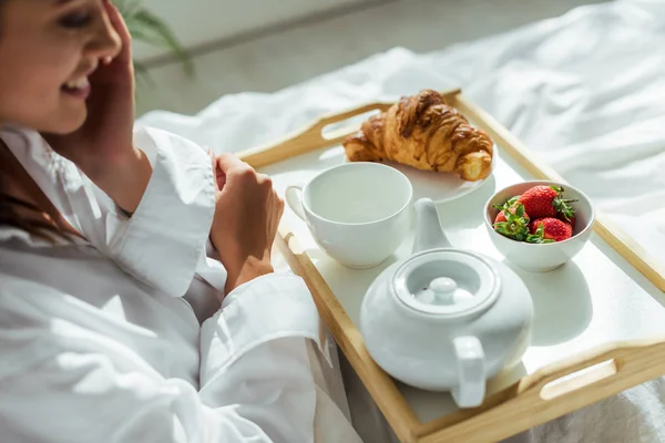 Vista cortada da mulher em camisa branca tomando café da manhã na cama de manhã — Fotografia de Stock