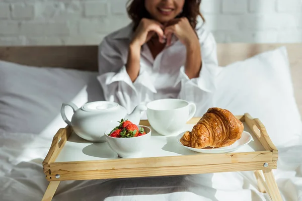 Cropped view of woman in white shirt having breakfast in bed at morning — Stock Photo