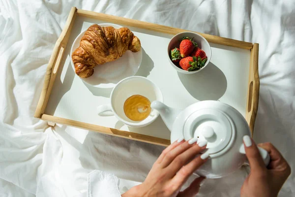 Vista superior da mulher derramando chá para xícara de manhã — Fotografia de Stock