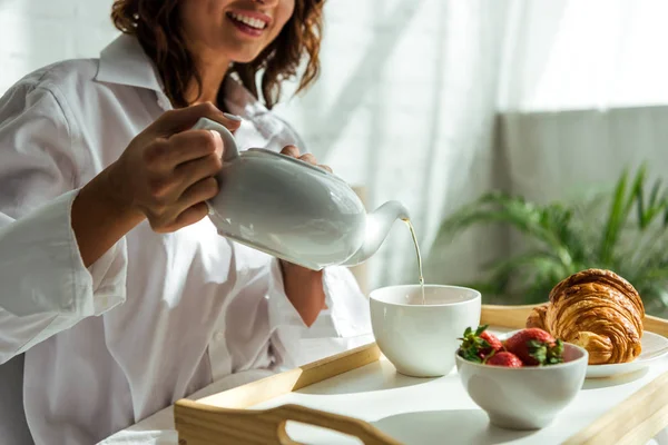 Vista ritagliata della donna versando tè a tazza al mattino — Foto stock