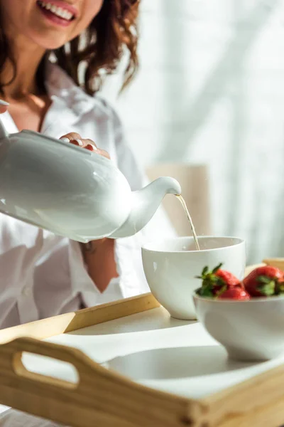 Vista recortada de la mujer vertiendo té a la taza por la mañana - foto de stock