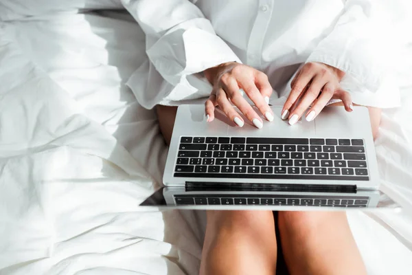 Vista recortada de la mujer en camisa blanca usando el ordenador portátil por la mañana - foto de stock