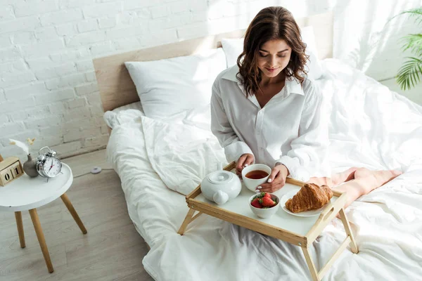 Attraente donna in camicia bianca che fa colazione a letto al mattino — Foto stock