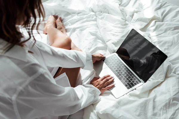 Vista recortada de la mujer en camisa blanca usando el ordenador portátil por la mañana - foto de stock