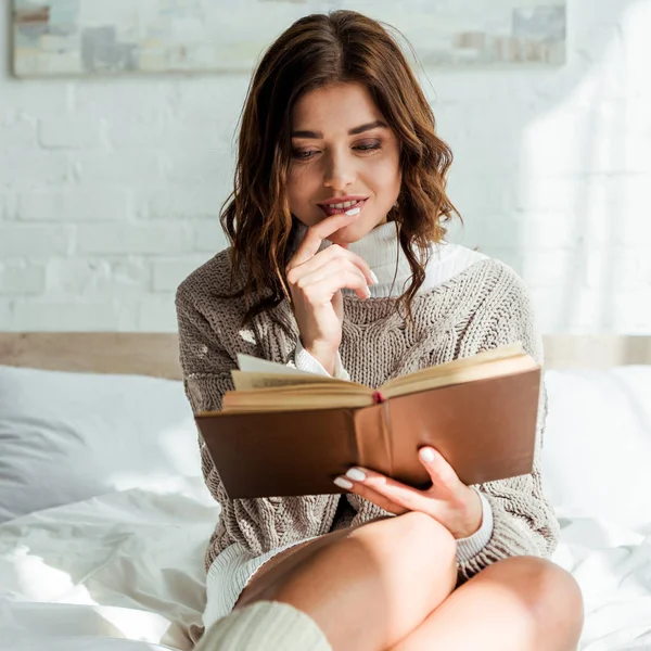 Mulher atraente em camisola cinza leitura livro de manhã — Fotografia de Stock