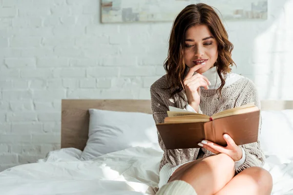 Attraktive Frau im grauen Pullover liest morgens Buch — Stockfoto