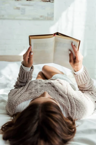 Foyer sélectif de la femme en chandail gris livre de lecture le matin — Photo de stock