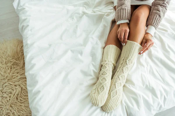 Cropped view of woman taking on knitted socks at morning — Stock Photo