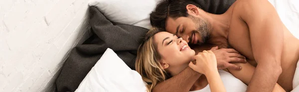 Feliz tierna pareja abrazándose en la cama por la mañana - foto de stock