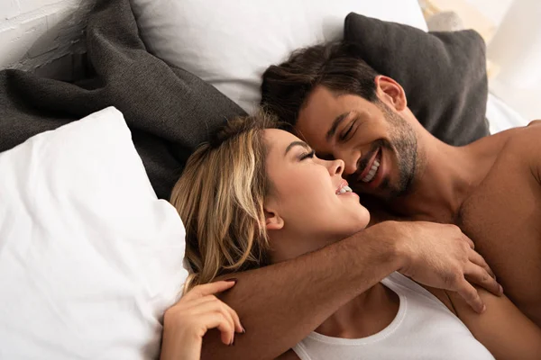 Lächelndes zartes Paar, das sich morgens im Bett umarmt — Stockfoto