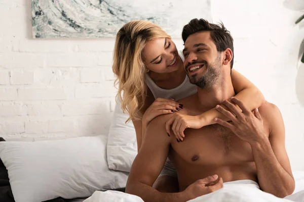 Heureux sourire couple étreignant dans le lit le matin — Photo de stock