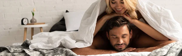 Bella coppia felice sdraiata sotto lenzuola al mattino — Foto stock