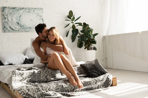 Homem terno feliz abraçando mulher na cama pela manhã — Fotografia de Stock