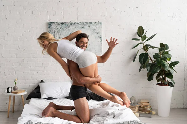 Hermosa pareja feliz divirtiéndose en la cama por la mañana - foto de stock