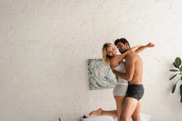 Feliz pareja bailando y abrazándose en el dormitorio por la mañana - foto de stock