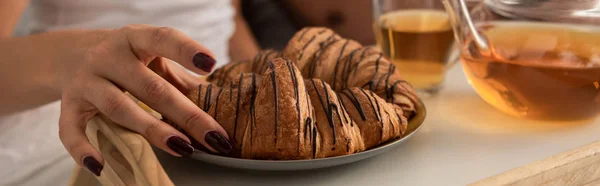 Vista ritagliata di coppia con croissant e tè per la prima colazione a letto — Foto stock